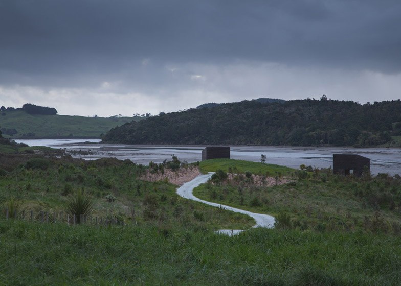 Blackened timber cabins by Cheshire Architects overlook the Tasman Sea